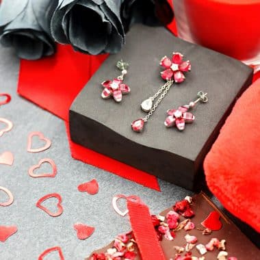 A romantic setup featuring jewelry, black roses, chocolates, and candles, perfect for Valentine's Day.